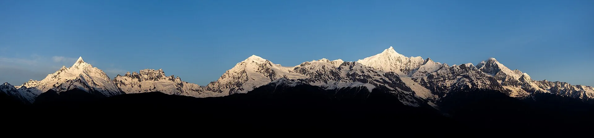 梅里雪山群峰全景:白雪覆盖的山脊在湛蓝天空下连绵起伏